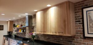 This image focuses the upper cabinets on the Sink/stove wall with the Brick wall behind them. It also shows the two floatings shelves, and the range hood.