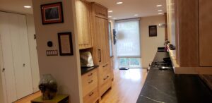 This image shows another view of the Fridge wall. The Fridge has custom wood door panels to conceal it better with the natural wood look on this wall. This view is from the back of the house in the dining room.