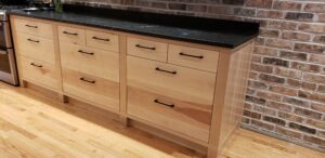 This image is of the Birch wood base cabinet to the right of the stove.  It features 11 drawers with 5 small drawers on the top, and 6 drawers on the bottom.