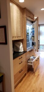 This image Shows The Fridge with Wood custom door panels partially open. The Freezer door is also partway open. 