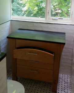 Cherry wood, closed storage Bath Vanity with Mortise and tenon details. This cabinet has three full drawers stacked on top of each other. The top drawer is curved to match the curved solid stretcher board above it.