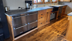 Another angle of the sink side base cabinets. The under counter drawer Fridge and Freezers on the far Left near outdoor shelter. To the right is a base cabinet with a bank of drawers on the left, and to the right of the bank of drawers. The smaller drawer on the Left matches the width of the Recycling and Garbage pull-out drawer with a shallow drawer beneath it. These two are set back 2" back from the upper drawer at the top. Around the sink there is a removable front to access the radiator beneath the sink. to the right of the sink there is a Double Dishdrawer. Next to the Dishdrawers and far right are a bank of 4 drawers with the top drawer 2" out from the lower three drawers. Glen Ellyn Hilltop Gallery