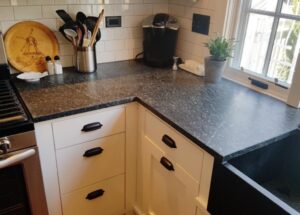 This image shows the lower corner base cabinets between the stove on the left and sink on the Soapstone sink on the right.